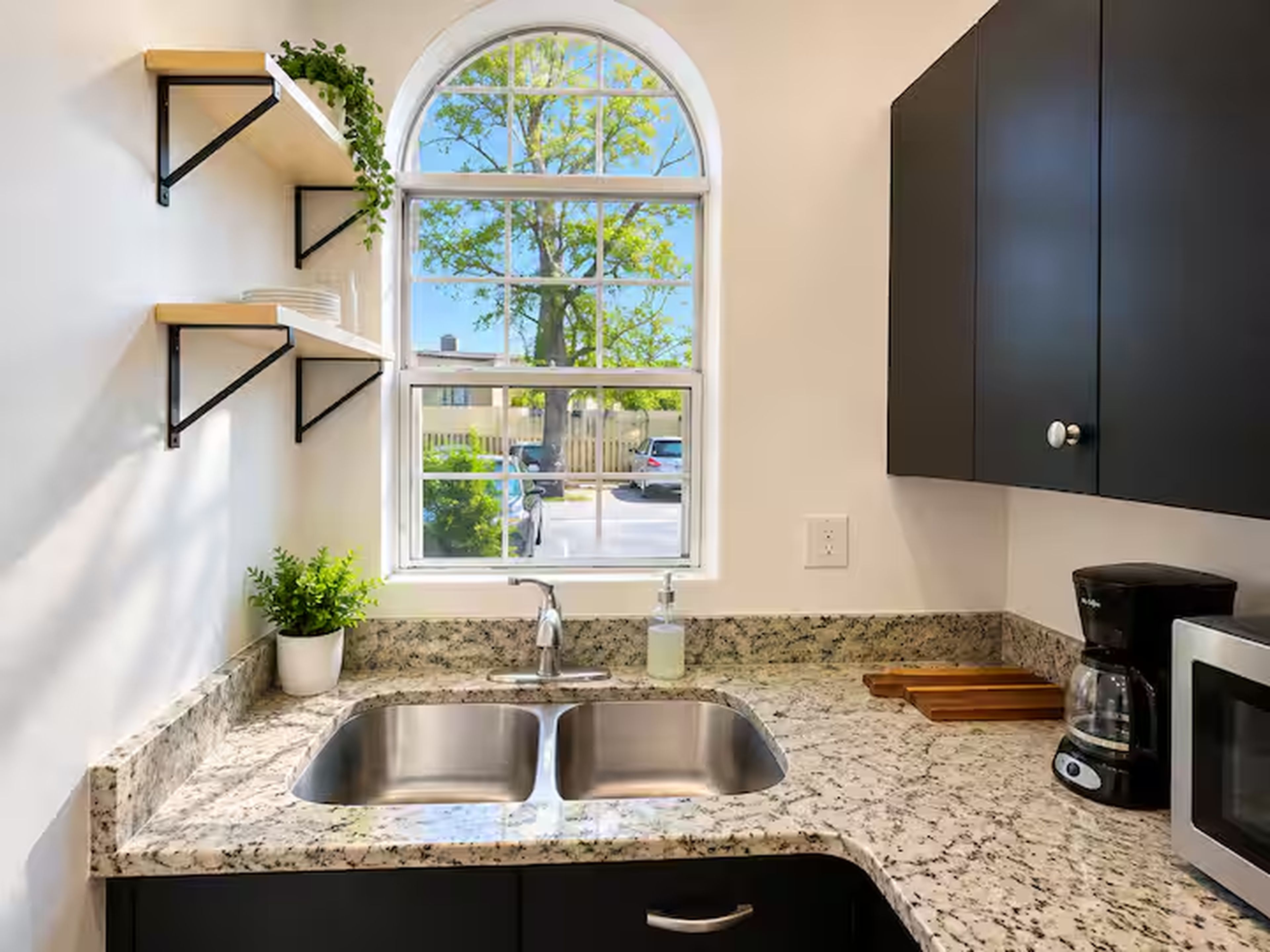 Una cocina con un lavaplatos doble, una ventana con vistas al exterior y armarios negros.