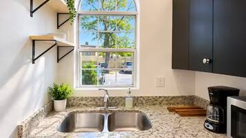 Una cocina con un lavaplatos doble, una ventana con vistas al exterior y armarios negros.