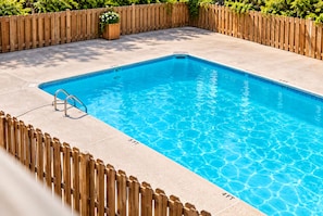 Ein rechteckiger Swimmingpool, umgeben von einem Holzzaun.