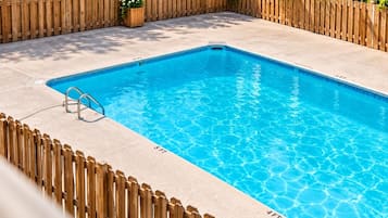 A rectangular swimming pool with a wooden fence surrounding it.
