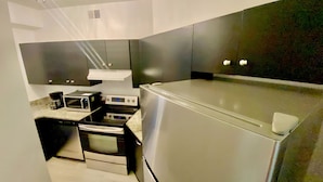 A modern kitchen with stainless steel appliances, a microwave, a stove, and a refrigerator. - Inside Wilmington’s Calmest In-Town Stay with Garden Patio! (Wilmington)