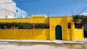 A yellow building with a green door, marked with '140 A' on the wall.