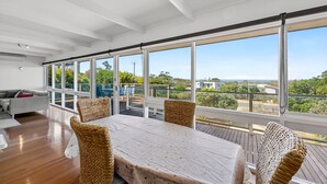 Amplia habitación con una gran mesa de comedor, sillas de mimbre y vistas al exterior a través de ventanas amplias.