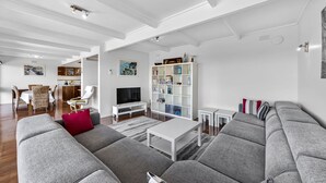 Una sala de estar moderna con sofás grises, una mesa de centro blanca, un televisor y una estantería.