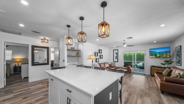 A spacious kitchen with a large island, pendant lighting, and a view to the outdoors. - New! Gulf Breeze - Stunning Heated Saltwater Pool & Spa with Sundeck, Apprx 1 Mile to Beach! (Naples)