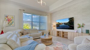 Una sala de estar moderna con un sofá color beige, una mesa de centro y un televisor de pantalla plana montado en la pared.