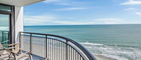 A balcony with a view of the ocean and beach.