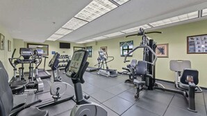 Ein Fitnessstudio mit verschiedenen Trainingsgeräten, darunter Laufbänder und Gewichte.