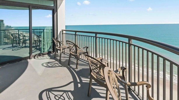 Ein Balkon mit Meerblick, ausgestattet mit Stühlen und Tischen.