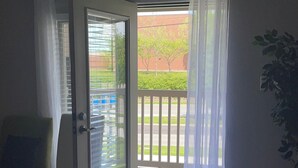 A room with a sliding glass door leading to a balcony with a white railing. - Walk /Funny Bone Comedy Club, Dining, Shopping, Free parking, Free Coffee, Patio (Dayton)