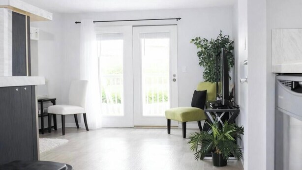 A modern living room with a white door, a black sofa, a green ottoman, and a potted plant. - Walk /Funny Bone Comedy Club, Dining, Shopping, Free parking, Free Coffee, Patio (Dayton)