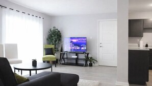 A modern living room with a flat-screen TV, a sofa, a coffee table, and a small plant. - Walk /Funny Bone Comedy Club, Dining, Shopping, Free parking, Free Coffee, Patio (Dayton)