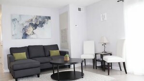 A modern living room with a sectional sofa, a round coffee table, a white armchair, and a small side table. - Walk /Funny Bone Comedy Club, Dining, Shopping, Free parking, Free Coffee, Patio (Dayton)