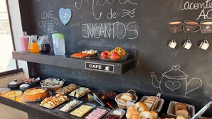A café counter with various food items and a chalkboard with writing. - POUSADA MARÉ DE ENCANTOS (Penha)