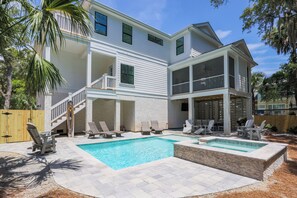 A two-story house with a swimming pool, outdoor seating, and a wooden fence. - Grand Opening June 13! New 6BR/5.5 Bath Luxury - Sleeps 18 - 4 rows to the Beach (Hilton Head Island)