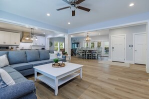 A spacious living area with a sofa, coffee table, and dining area with chairs and a chandelier. - Grand Opening June 13! New 6BR/5.5 Bath Luxury - Sleeps 18 - 4 rows to the Beach (Hilton Head Island)