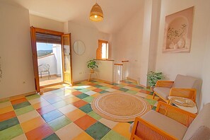 A room with a checkered floor, wicker furniture, a round rug, and a view through an open door. - Costa Del Sol apartment in the village of Frigiliana (Frigiliana)