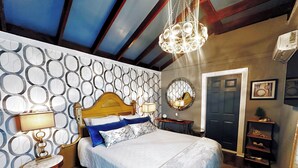 Ein ordentlich eingerichtetes Schlafzimmer mit einem großen Bett, Nachttischen, einem Spiegel und einer Chandelier.