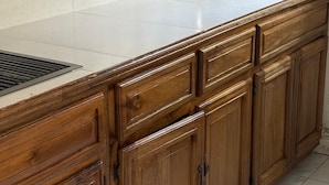 A kitchen with wooden cabinets, a white countertop, and a tiled backsplash.