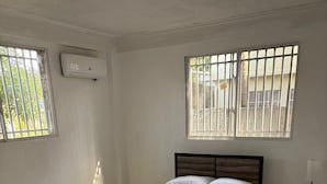 A bedroom with a bed, a nightstand, and a window with bars.