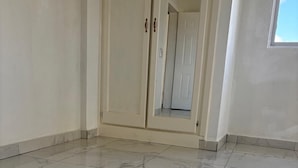 A room with a tiled floor, a wardrobe with two doors, and a window.