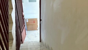 A hallway with marble flooring and a wooden railing.