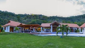 Ein Resort mit mehreren Villen, einem Schwimmbad und einer üppigen Grünlandschaft.