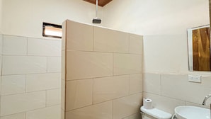 Et badeværelse med toilet, håndvask og bruseområde.
