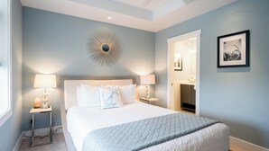 Een slaapkamer met een bed, twee nachtkastjes met lampen, een wandlamp en een lijst met een afbeelding.