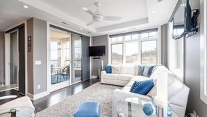 Een moderne woonkamer met een witte bank, een glazen salontafel en een groot raam.
