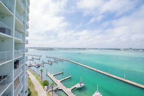 Un immeuble de grande hauteur doté de balcons donnant sur une marina avec des quais et un bateau.