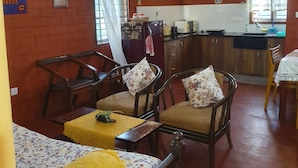 Un salon chaleureux avec un coin repas, des meubles en bois, un réfrigérateur et une cuisine en arrière-plan.
