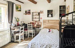 Un dormitorio con cama, escritorio, silla, estanterías y ventana.