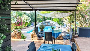 A covered patio area with a pool table, chairs, and a table under a canopy. - Maison piscine à Anduze (Anduze)