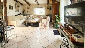 A cozy living room with a sofa, armchair, and coffee table, a television, and various decorative items. - Maison piscine à Anduze (Anduze)