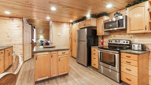 Eine Küche mit Holzwandverkleidung, inklusive Kühlschrank, Herd, Mikrowelle und Toaster.