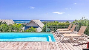 A wooden deck with a pool and lounge chairs overlooking a coastal view. - Villa Thomarine Vue Mer & Saint-Barth, Piscine (Orient Bay)