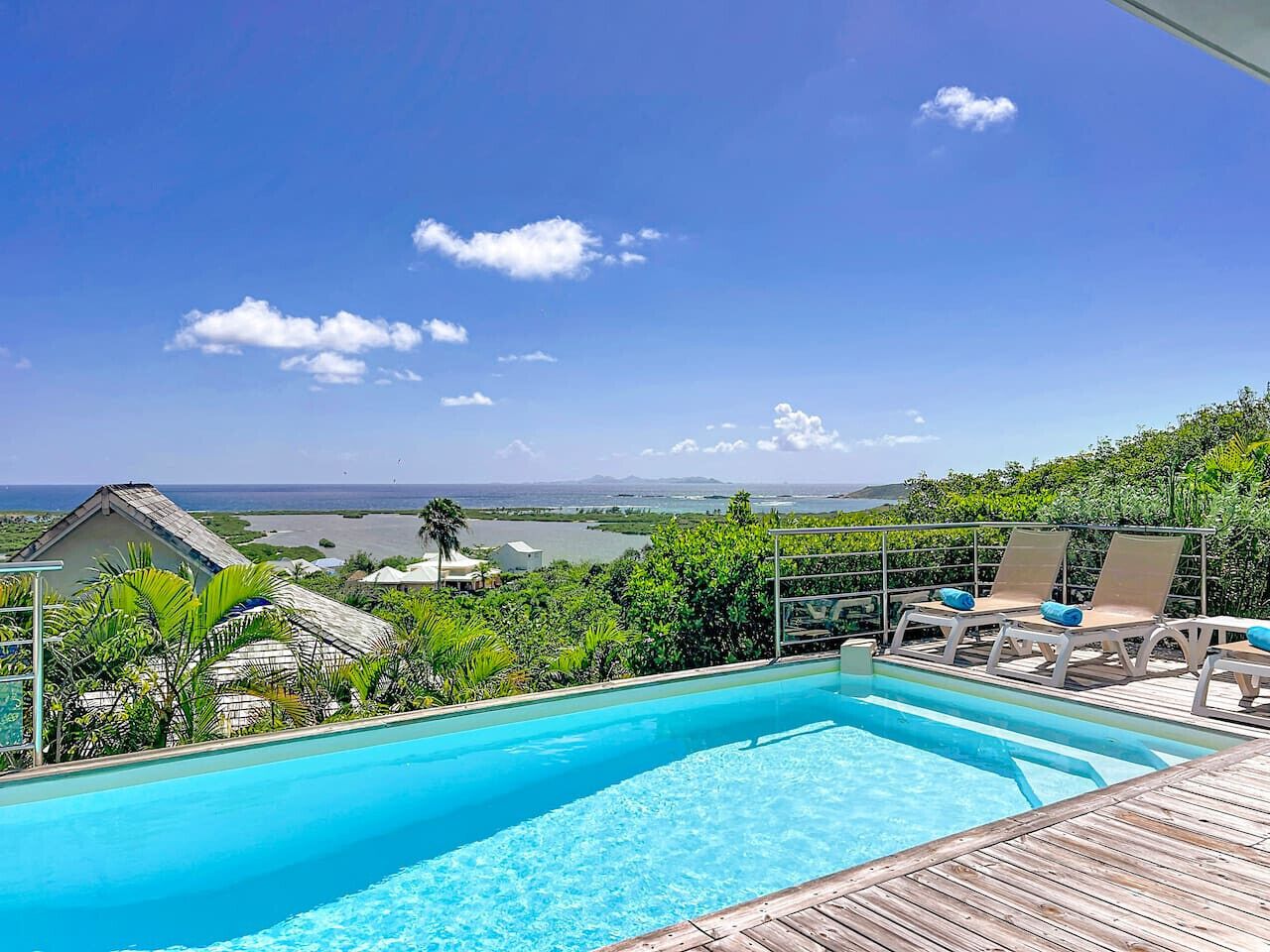 A swimming pool with lounge chairs and a view of the ocean.