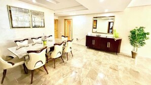 A dining area with a marble table and chairs, a dark wooden cabinet, and a large mirror on the wall. - Reda's'Apparts (Downtown - Wifi 200 Mb) (Fès)