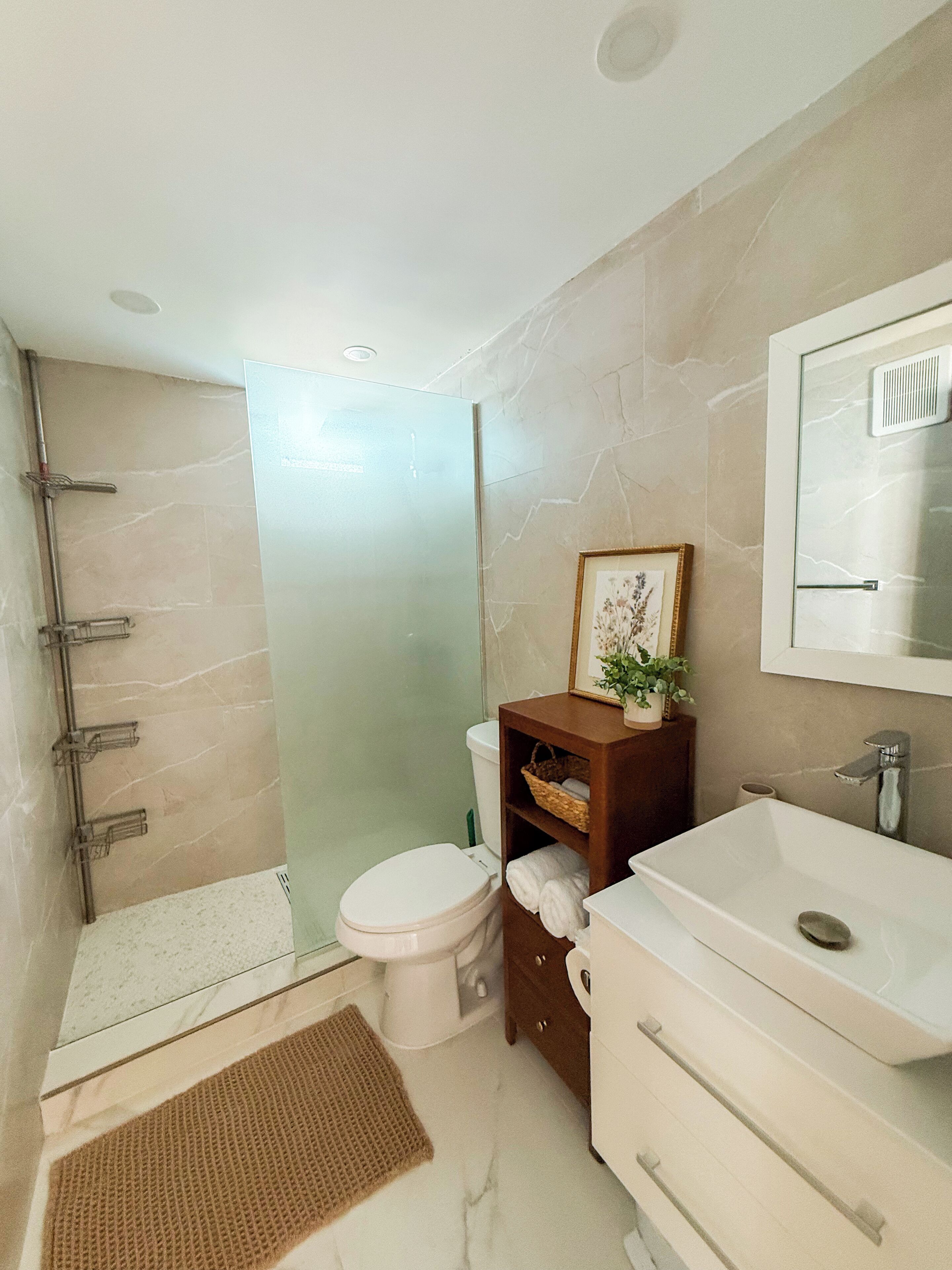 Une salle de bain équipée de toilettes, d’un lavabo, d’une douche et d’un miroir.