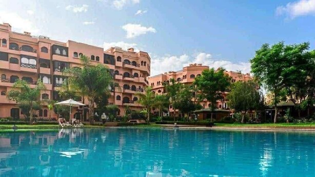 Un hotel con piscina, varios balcones y abundante vegetación.