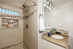 Une salle de bain équipée d’une douche, d’un lavabo, d’un miroir et d’un porte-serviettes.