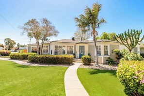 A single-story house with a front yard, a pathway leading to the front door, and a palm tree. - Pacific Beach 4 Bedrm Retreat+Studio+Hot Tub+Yard (San Diego)