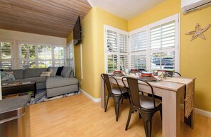 A room with a dining table, chairs, a sofa, and a TV. - Pacific Beach 4 Bedrm Retreat+Studio+Hot Tub+Yard (San Diego)