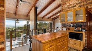 Una cocina amplia con una isla de madera, armarios empotrados y vistas al campo.