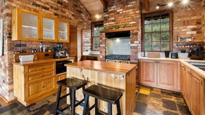Una cocina rústica con armarios de madera, una isla central y una pared de ladrillo.