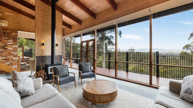 Amplia sala de estar con un gran techo de madera, una chimenea y vistas al exterior.