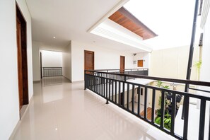 Een ruim, modern interieur met een balkon, een houten plafond en een betegelde vloer.