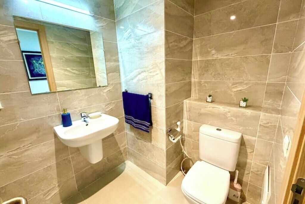 A bathroom with a pedestal sink, a toilet, and a mirror.