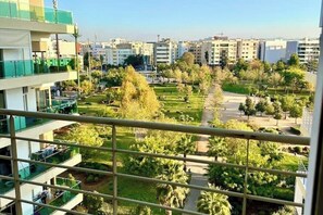 Un edificio residencial con balcones, un parque verde y una vista despejada del paisaje urbano.